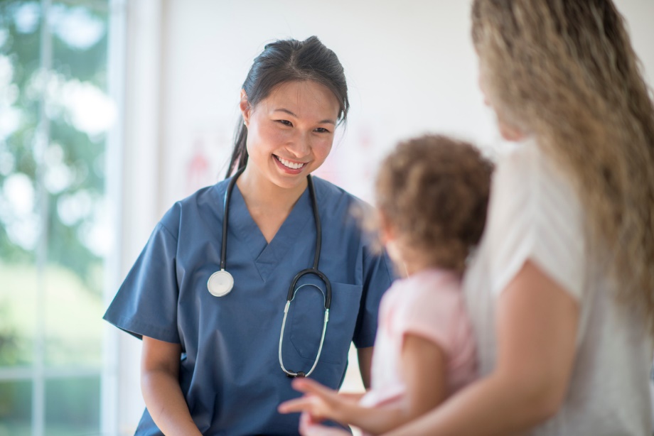 A doctor with a child and a stethoscope Description automatically generated